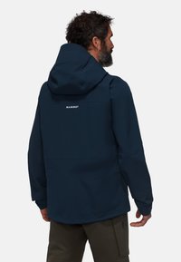 Veste Mammut bleu marine avec capuche, en tissu durable, à coupe décontractée et au design minimaliste avec un logo sur le haut du dos.