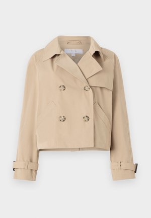 Beige cropped trench coat med dobbeltradet knappestolpe, bred krage og sidelommer. Har mansjettstropper ved ermene.
