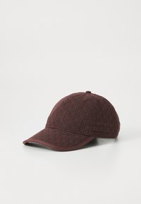 Casquette de baseball marron avec un motif géométrique en diamants noirs et un petit bouton sur le dessus, présentée sur fond blanc.