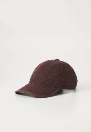 Bruine baseballcap met zwart geometrisch diamantpatroon en een kleine knop bovenop, weergegeven tegen een witte achtergrond.