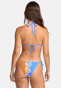 Zestaw bikini z niebieską górą na halter i dolnym części w kolorze pomarańczowo-niebieskim. Posiada kwiatowe wzory oraz sznurki przy szyi i bokach dla regulowanego dopasowania.