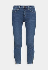 Jeans de mezclilla azul de tiro medio con un corte ajustado, que cuentan con bolsillos frontales, herrajes dorados y detalles con cremallera en los tobillos para un ajuste ajustable.