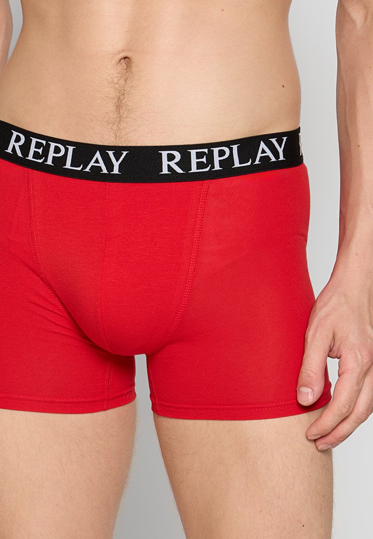 Rote Baumwoll-Boxershorts mit einem schwarzen Bund, der das Logo "REPLAY" in Weiß trägt. Glatte Textur und taillierte Passform.