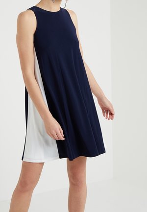 Robe sans manches à blocs de couleur bleu marine et blanc portée par une personne, cintrée en haut et évasée à l'ourlet au-dessus des genoux.