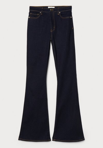 Mørkeblå utsvingte jeans laget av denim, med gule sømmer, frontlommer og standard linning med knappelukking.