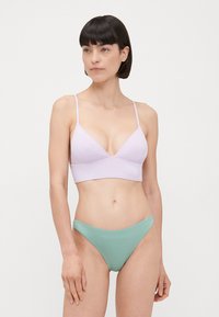 Világoslila bralette vékony pántokkal, háromszög alakú kosarakkal és varrásmentes dizájnnal, párosítva mentazöld bikini alsóval, alacsony derékkal és sima felülettel.