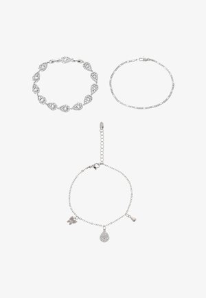 Három ezüst karkötő: egy szív alakú láncszemekkel, egy vékony lánc, és egy charmokkal díszített (pillangó, csepp alakú) karkötő, bogárkapoccsal.