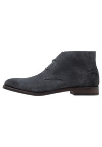 Bottines en suède gris avec un bout étroit, des accents cousus, deux œillets pour les lacets et un petit talon rectangulaire en bois.