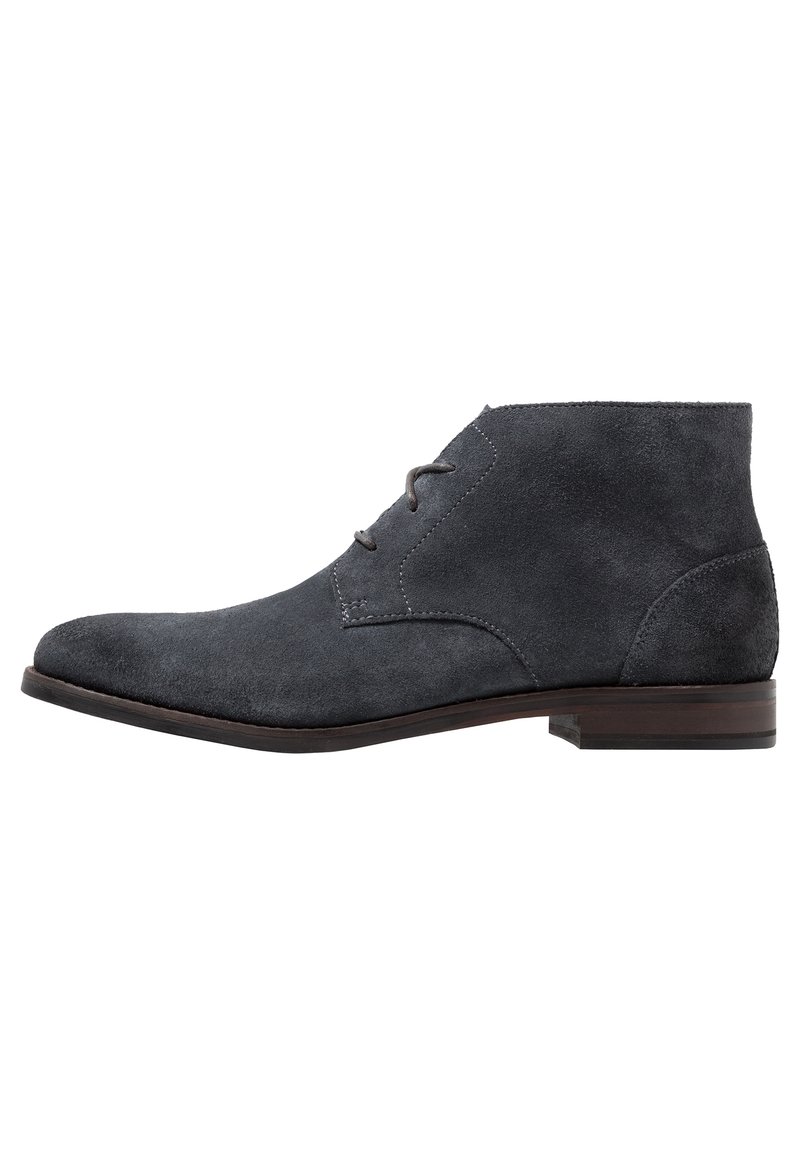 Bottines en suède gris avec un bout étroit, des accents cousus, deux œillets pour les lacets et un petit talon rectangulaire en bois.