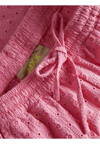Rožinė medvilnės apranga su tekstūriniu audiniu ir gėlių raštais, surinkta juosmens linija ir sukti raištis reguliuojamam pritaikymui.