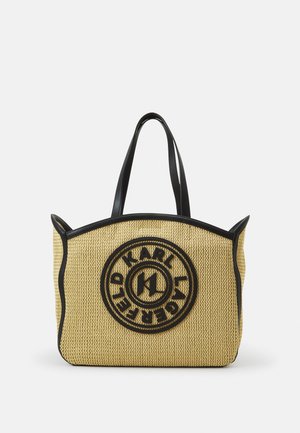 Yellow woven tote bag, featuring black leather handles and trim, a circular logo design on the front, and a structured shape.
