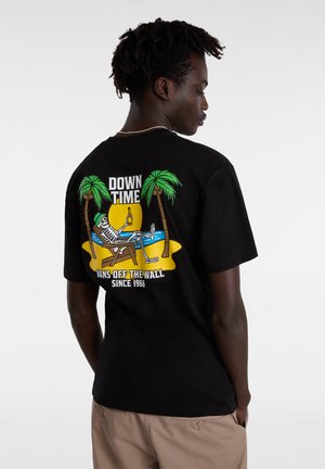 Camiseta de algodón negra con un gráfico colorido de un esqueleto en una silla de playa, palmeras y el texto "DOWNTIME". Diseño de corte clásico.