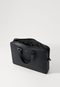 Bolso de cuero negro para portátil con asas dobles, cierre de cremallera y una superficie texturizada. El interior está forrado con tela para protección.
