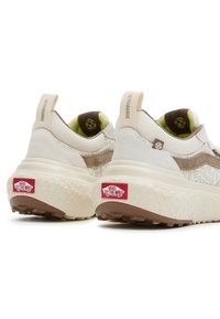 Sneakers beige chiaro con parte superiore in rete testurizzata, accenti crema, suola in gomma spessa e toppe con logo rosso sul tallone. Presentano linguette per il pull.