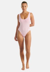 Růžové jednodílné plavky se širokými ramínky, výstřihem do U a vysokým střihem. Na levé dolní straně je bílý detail loga.