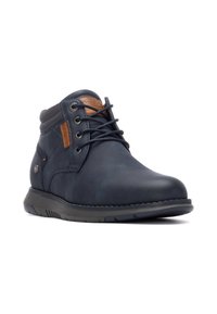 Botín de hombre de piel azul marino con acentos marrones, puntera redonda, diseño con cordones, suela de goma y cuello acolchado para mayor comodidad.