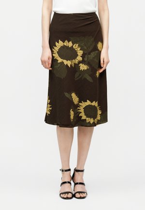 Rjava midi krilo z velikimi rumenimi motivi sončnic, kombinirano s črnimi sandali z naramnico in belo majico.