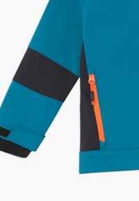 Manica di giacca teal e nera con una tasca con zip arancione. Realizzata in materiale liscio, presenta una fascetta in Velcro sul polsino per la regolazione.