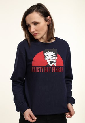 Mørkeblå, langærmet sweatshirt med et cartoon-illustration af en karakter med teksten "FLIRTY BUT FIERCE" i rød. Blandingsstof af bomuld.