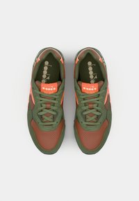 Sneakers with green and brown synthetic upper, orange accents, perforated texture on the toe, and lace-up closure. Features logo on tongue.