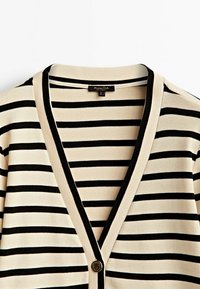 Sweter w paski z dekoltem w kształcie litery V, w kolorze kremowym i czarnym, z teksturowanym wykończeniem dzianiny oraz pojedynczym zapięciem na okrągły guzik.
