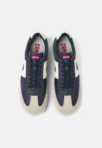 Navy and cream sneakers feature a smooth leather finish with a suede toe cap. Laces and padded collar in navy; red logo accent on tongue.