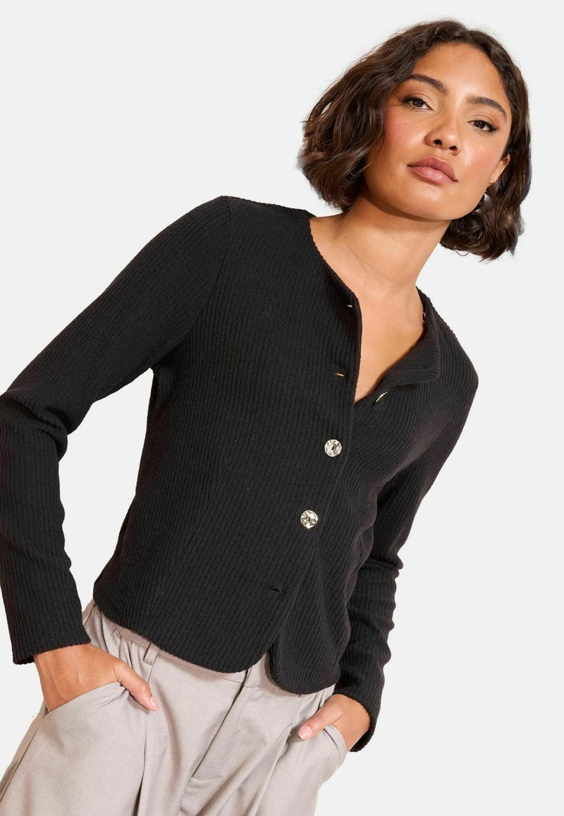 Crni rebrasti kardigan s okruglim izrezom, dugim rukavima i dekorativnim gumbima. Ima zakrivljeni rub i teksturirani materijal.