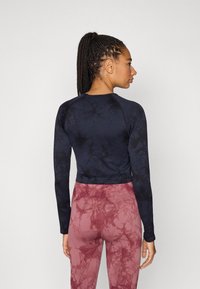 Μπλούζα μακρυμάνικη με σκούρο μπλε σχέδιο tie-dye και στρογγυλή λαιμόκοψη, συνδυασμένη με ροζ κολάν μαρμάρινο, ψηλόμεσο.