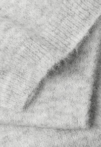 Tessuto lavorato a maglia grigio chiaro con una texture morbida, che mostra sottili variazioni di tonalità e una superficie leggermente pelosa.