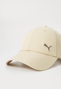 Beige baseball cap made of fabric, featuring six panels, curved visor, and a metallic Puma logo on the front left side.