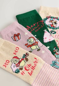 Four pairs of festive socks: pink with a gift, green with "Merry Christmas," beige with a bear and text, and striped accents. Cotton blend.