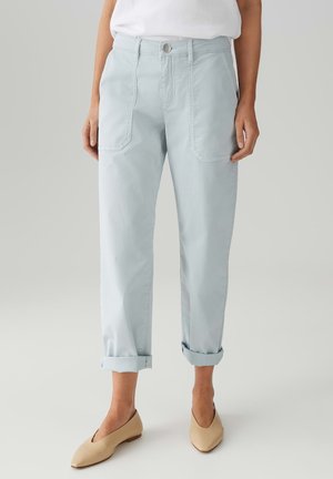 Pantaloni di cotone azzurro chiaro con risvolti, dotati di ampie tasche anteriori e chiusura con bottone in vita. Texture liscia.
