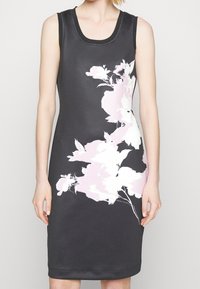 Černé bezramínkové šaty s květinovým vzorem v jemně růžové a bílé barvě. Úzký střih s kulatým výstřihem a hladkou texturou látky.