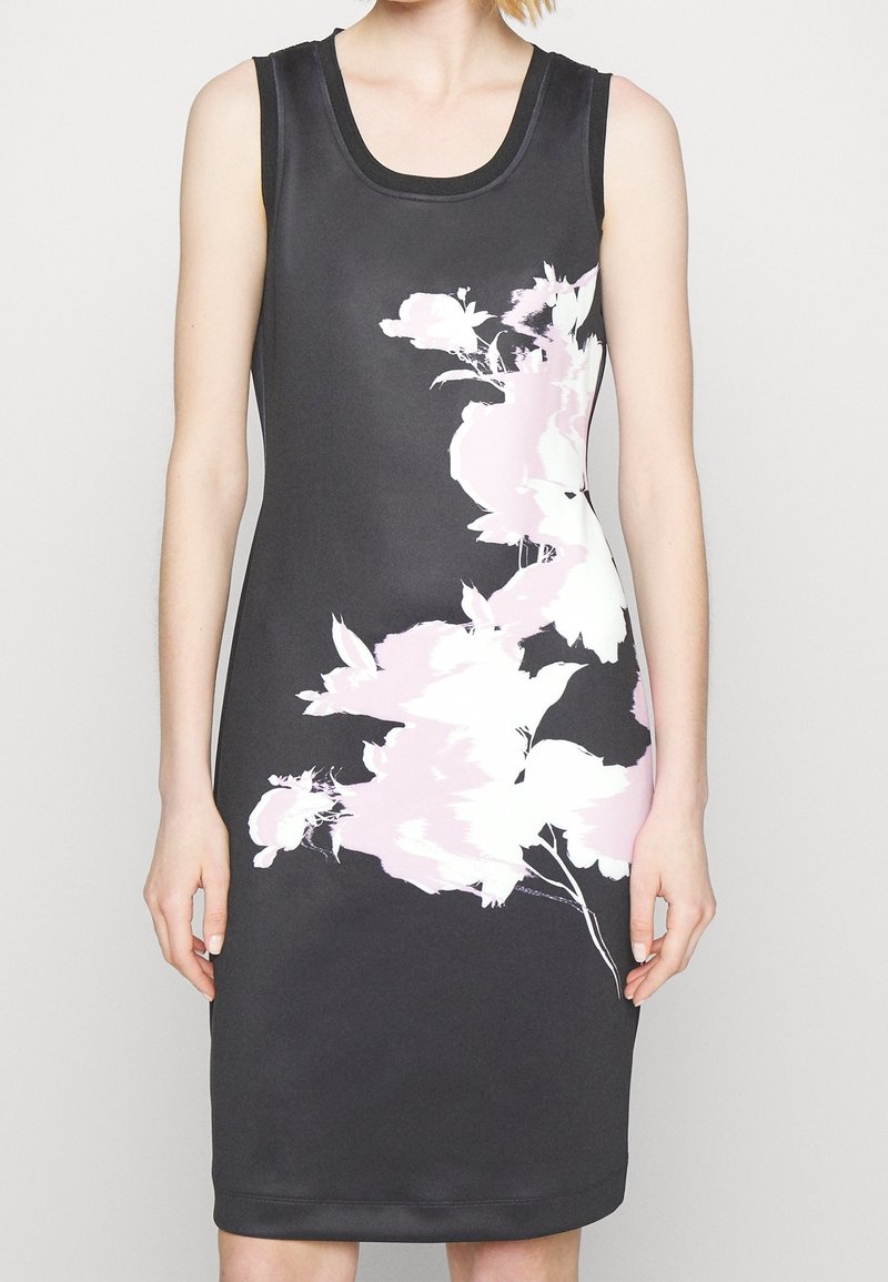 Černé bezramínkové šaty s květinovým vzorem v jemně růžové a bílé barvě. Úzký střih s kulatým výstřihem a hladkou texturou látky.