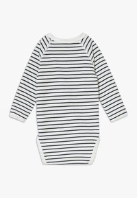 Body intero per neonato a maniche lunghe con sfondo bianco e righe orizzontali blu navy. Collo arrotondato, chiusure a pressione sul fondo. Materiale in cotone.