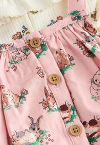 Rochie roz fără mâneci, cu imprimeuri cu iepurași și accente florale, cu nasturi și textură ușoară, concepută pentru confort și stil.