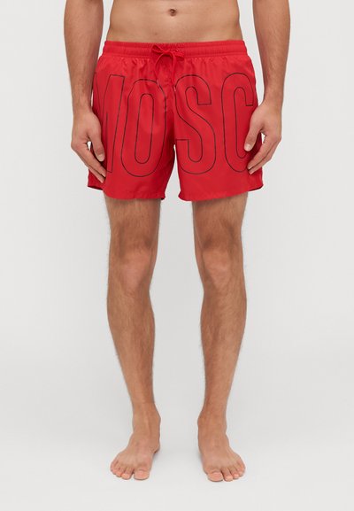 Red swim shorts with a drawstring waist, featuring large black "MOSC" lettering across the front. Made of lightweight, smooth fabric.