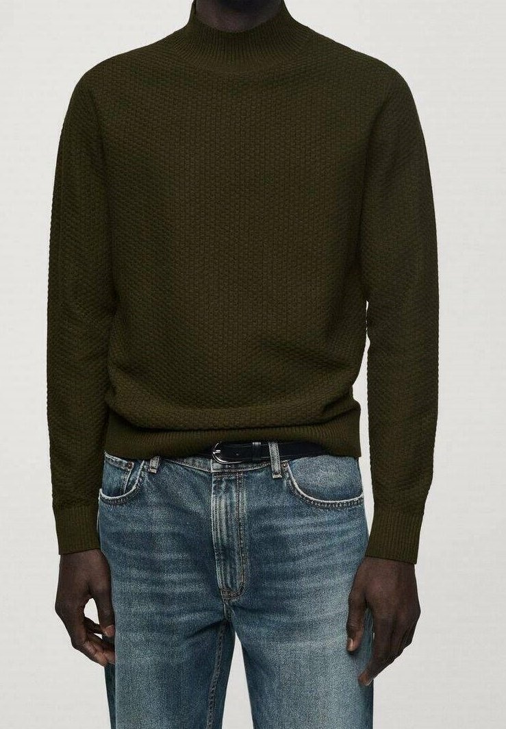 Pull en maille texturée vert foncé porté avec un jean en denim bleu et une ceinture noire, présenté des épaules jusqu'aux hanches.
