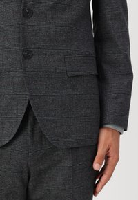 Veste de costume à carreaux gris en tissu texturé, dotée de deux boutons noirs, d'une poche poitrine simple et d'une poche à rabat sur le côté.