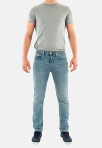 Camiseta gris de manga corta combinada con jeans de mezclilla azul claro. Los jeans tienen un diseño clásico de cinco bolsillos y un ligero desgaste, usados con zapatillas navy.