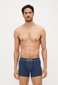 Námornícky modré bavlnené boxerky s bielym pruhovaným pásom s logom "Levi's", hladká textúra a priliehavý strih.