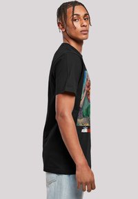 Camiseta de algodón negra con un gráfico colorido en la parte frontal que representa un gesto de mano, mangas cortas y cuello redondo.