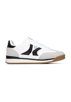 Zapatilla blanca y gris con detalles negros, diseño con cordones y suela de goma marrón mostrada en vista lateral sobre un fondo blanco.
