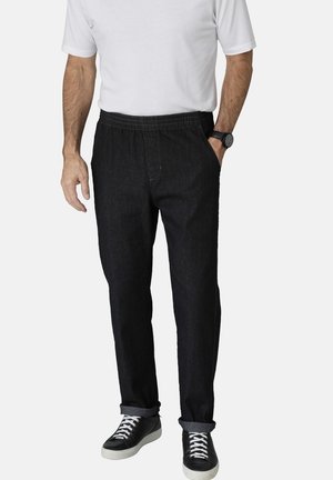 Dark blue denim pants with an elastic waistband, straight cut, and rolled cuffs. Paired with black and white sneakers for contrast.