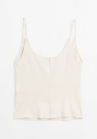 Camisole beige clair ajustée avec fines bretelles réglables ; elle présente une fermeture éclair au dos et des coutures verticales discrètes.