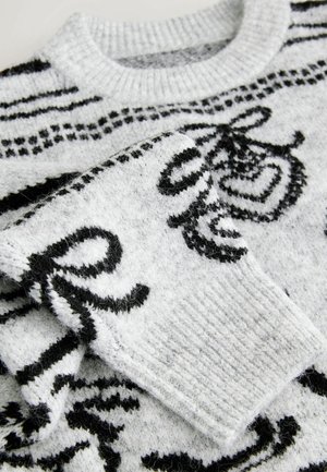 Pull en maille gris avec motif abstrait noir, poignets côtelés et texture duveteuse. Encolure ronde et détail des manches repliées visibles.