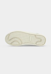 Zool van een witte sneaker met een gestructureerd grip patroon en de merknaam "ONITSUKA" in het midden geperst.