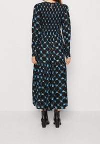 Musta pitkähihainen mekko sinisellä kukkakuviolla, smockattu vyötärö ja kerroksellinen hame. Yhdistetty mustiin korkokenkiin.