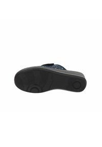 Suola in gomma nera di una scarpa, con una superficie a motivo e un design strutturato. Include un dettaglio circolare vicino al tallone.