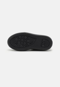 Semelle en caoutchouc noir avec un motif de grip texturé, présentant un design hexagonal et des lignes horizontales supplémentaires pour plus de traction.